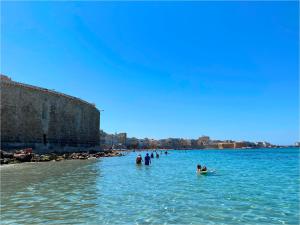 a group of people in the water on a beach at Residenza San Teodoro in Trapani