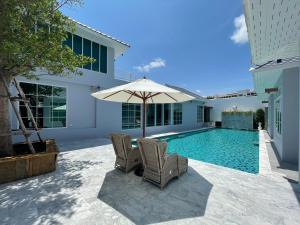 a swimming pool with two chairs and an umbrella at Skeyndor Health & Resort in Na Jomtien
