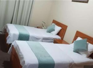 two beds in a hotel room with green and white sheets at Al Jazeerah Hotel in Sharjah