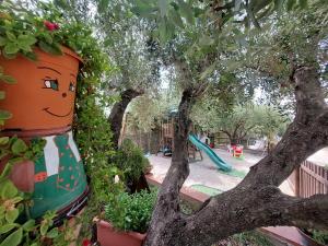um grande potenciômetro sentado em uma árvore ao lado de um playground em Parco Esmeralda - Family Residence e Breakfast em Marina di Camerota