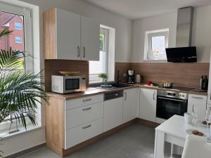 a kitchen with white cabinets and a microwave at Ferienwohnung Bernsteinzauber städtische Bestlage in Ribnitz-Damgarten