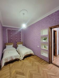 a bedroom with two beds and a purple wall at Jacquard Apartment in the centre of Kutaisi in Kutaisi