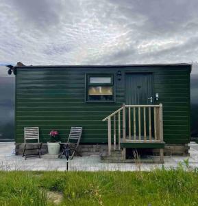 ein grünes Haus mit 2 Stühlen und einer Veranda in der Unterkunft Runaway Northumberland in Morpeth