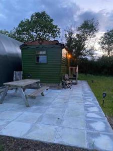 a green cabin with a picnic table and a bench at Runaway Northumberland in Morpeth