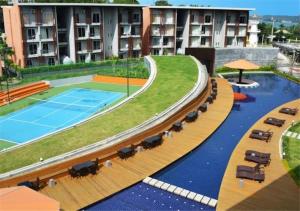 uma piscina com um campo de ténis e cadeiras e um edifício em Suite in Replay at Bangrak Beach em Nathon Bay