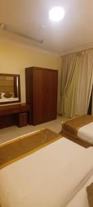 a bedroom with two beds and a dresser and a mirror at ريف للشقق الفندقية in Medina