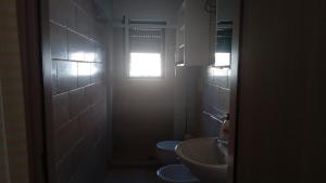 bagno con due servizi igienici, lavandino e finestra di Casa Polinisso a Carovigno