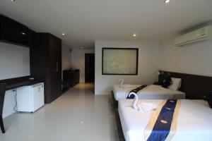 Habitación de hotel con 2 camas y TV de pantalla plana. en Oceanview Treasure Hotel and Residence, en Patong Beach