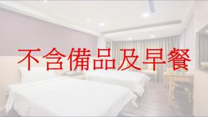 two beds in a room with chinese writing on the wall at KKS Hotel in Hualien City