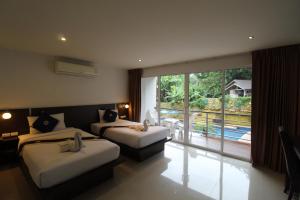 a hotel room with two beds and a large window at Oceanview Treasure Hotel and Residence in Patong Beach