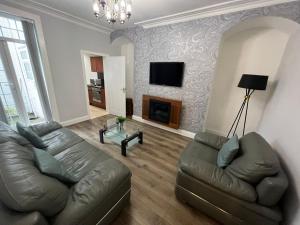 a living room with a leather couch and a fireplace at Alexander Apartments South Shields 2 in South Shields