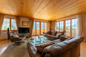 una sala de estar con muebles de cuero y techo de madera. en Chalet Solidage en Rougemont