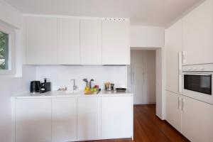 a white kitchen with white cabinets and a sink at Ruvigliana Amazing View - Happy Rentals in Lugano