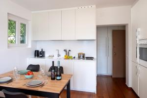 a kitchen with a wooden table and white cabinets at Ruvigliana Amazing View - Happy Rentals in Lugano