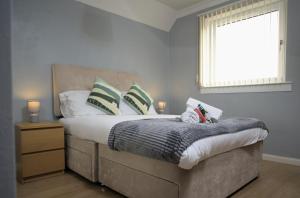 um quarto com uma cama com almofadas e uma janela em Modern 2-Bed Haven, FREE PARKING em Edinburgo