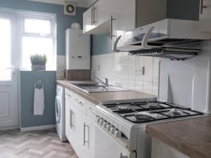 a white kitchen with a stove and a sink at Pass the Keys Flat close to amenities in Scunthorpe