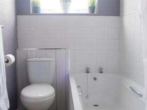 a white bathroom with a toilet and a bath tub at Pass the Keys Flat close to amenities in Scunthorpe