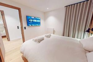 um quarto com uma cama branca e uma televisão na parede em Appartement neuf à Mottaret / A12 em Les Allues