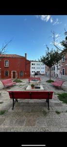 un groupe de bancs rouges assis dans une cour dans l'établissement Appartement GIUDECCA, à Venise