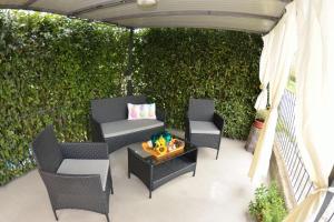 een patio met stoelen, een tafel en een heg bij Casale Geniva with Private Pool - Happy Rentals in Massarosa