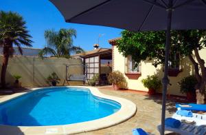 a swimming pool with an umbrella next to a house at Casa Limón - Ferienhaus - Pool - Klimaanlage - W-Lan in Chiclana de la Frontera