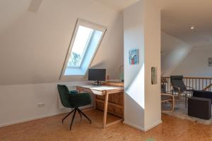 an attic office with a desk and a window at Ferienwohnung Schwanensee in Kölpinsee
