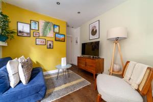een woonkamer met een blauwe bank en een tv bij The Finsbury Park Collection in Londen