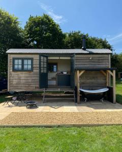 une petite maison avec un bateau sur une terrasse dans l'établissement The Rabbit Warren Shepherd Hut, à Ketton