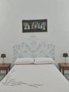un letto bianco con testiera bianca e un dipinto sopra di esso di La casa di nonna Laura a Lizzanello