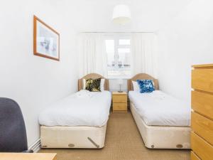 2 łóżka pojedyncze w pokoju z oknem w obiekcie Pass the Keys - Beautiful Flat with balcony in Swiss Cottage, London w Londynie