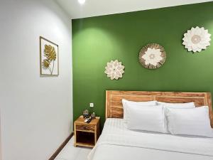 Dormitorio verde con cama y pared verde en Lubdhaka Canggu, en Canggu