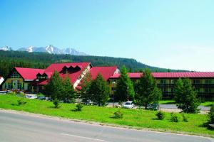 un grand bâtiment avec des toits rouges et un parking dans l'établissement Hotel RYSY, à Tatranska Strba