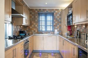 a large kitchen with wooden cabinets and a sink at Windrush Lake 66, Sun Kissed Lodge in South Cerney