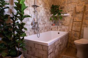 uma casa de banho com uma banheira numa parede de tijolos em Amygdalia Traditional House em Chania Town