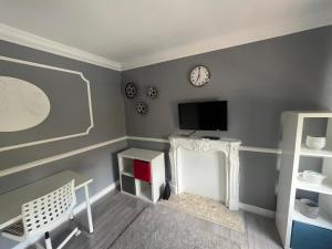 sala de estar con TV y chimenea blanca en The E17 Suite en Londres