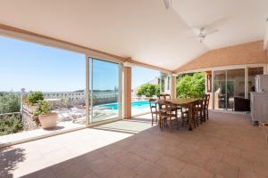 un patio con mesa, sillas y piscina en Maison avec piscine et belle vue, en Lédenon