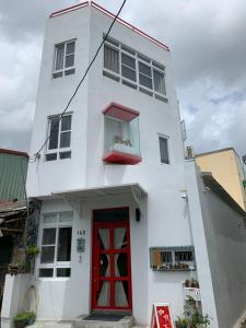 uma casa branca com uma porta vermelha em 177 Beigang Homestay em Beigang