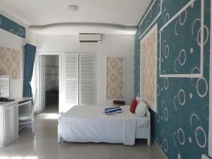 a bedroom with a white bed and a green wall at Muine Sun & Sea Resort in Mui Ne