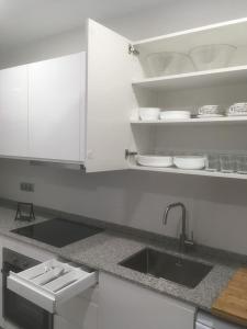eine weiße Küche mit einem Waschbecken und einer Arbeitsplatte in der Unterkunft Apartamento 1ª linea de mar in Comarruga