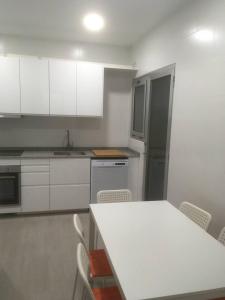 uma cozinha com armários brancos e uma mesa e cadeiras brancas em Apartamento 1ª linea de mar em Comarruga