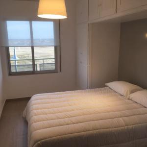 um quarto com uma cama grande e uma janela em Apartamento 1ª linea de mar em Comarruga