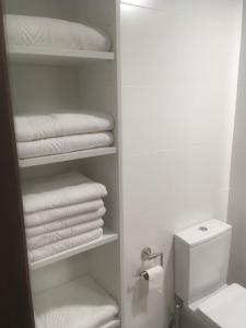 uma casa de banho com um armário e toalhas brancas em Apartamento 1ª linea de mar em Comarruga