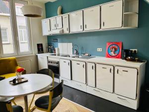 a kitchen with white cabinets and a table and a dining room at foodiejive appartement 2 in Antwerp