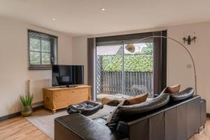 a living room with a leather couch and a television at Timber Lodge in Tackley