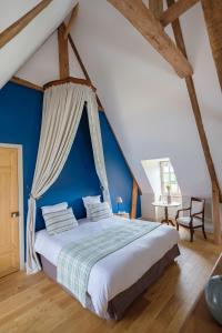 ein Schlafzimmer mit einem großen Bett mit blauer Wand in der Unterkunft Le Domaine de Ravenoville - Pierres d'Histoire in Ravenoville