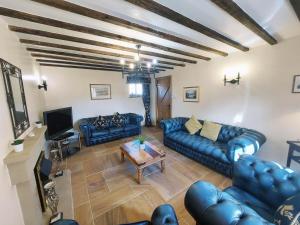 a living room with blue leather couches and a table at The Old Mill Barn with Hot Tub and Private Pool in Wirral