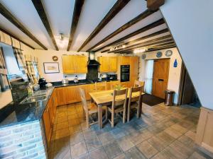a kitchen with wooden cabinets and a table and chairs at The Old Mill Barn with Hot Tub and Private Pool in Wirral