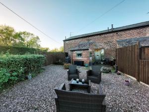 a backyard with chairs and a table and a brick building at The Old Mill Barn with Hot Tub and Private Pool in Wirral