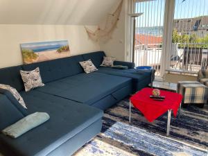 ein Wohnzimmer mit einem blauen Sofa und einem roten Tisch in der Unterkunft Ferienwohnung Fördefreude in Wassersleben