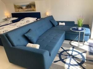 ein blaues Sofa im Wohnzimmer mit einem Bett in der Unterkunft Ferienwohnung Fördefreude in Wassersleben